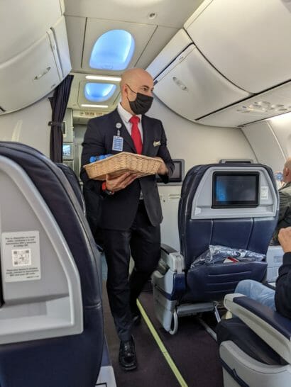 a man wearing a face mask and holding a basket in an airplane