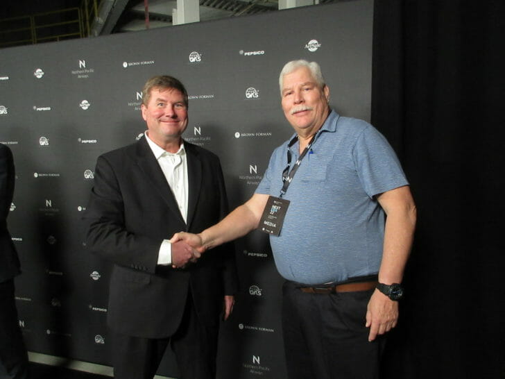 two men shaking hands in front of a wall