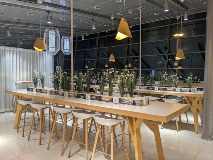 a long table with white chairs and flowers