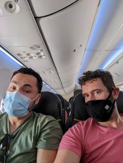 two men wearing face masks on an airplane