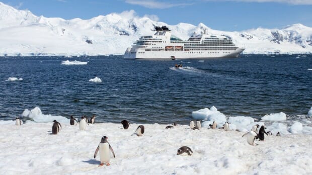 a cruise ship in the water with penguins on the snow