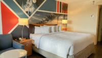 a bed with white sheets and a lamp next to a table