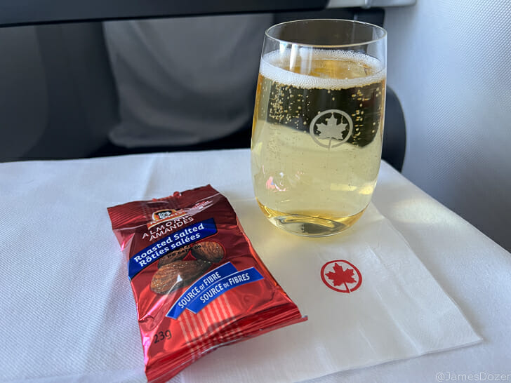 a glass of beer and a packet of nuts on a white napkin