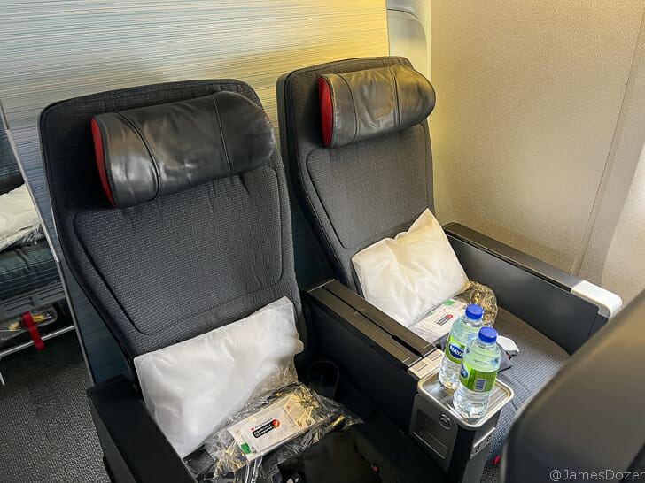 two chairs with pillows and a drink on the side