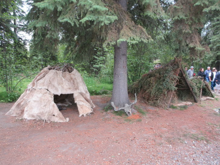 a group of people standing next to a teepee