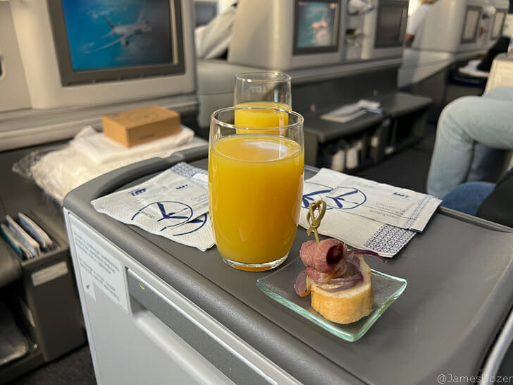 a glass of orange juice and a sandwich on a tray
