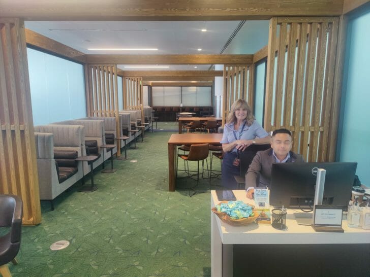 a man and woman sitting at a desk in a room with chairs