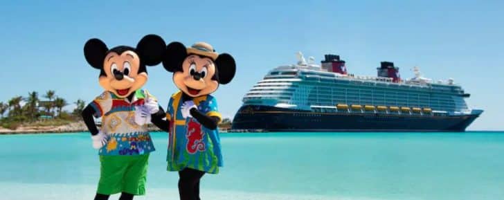 a couple of people in clothing standing on a beach next to a cruise ship