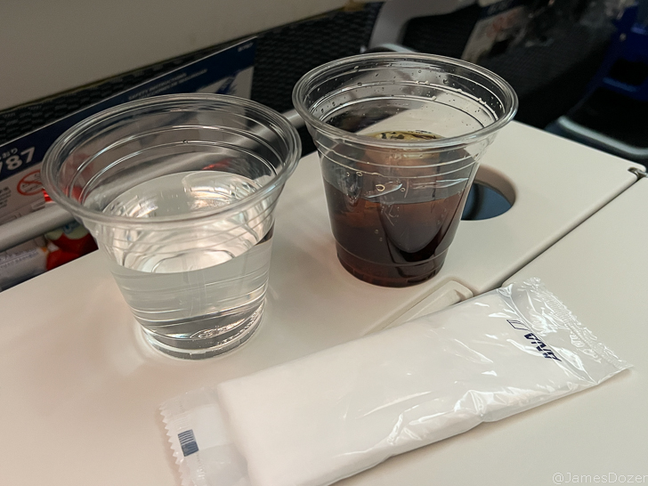 two plastic cups of liquid and a packet of sugar on a table