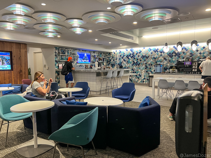 a group of people sitting in a room with blue chairs and tables