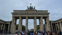 a large stone structure with a statue on top with Brandenburg Gate in the background