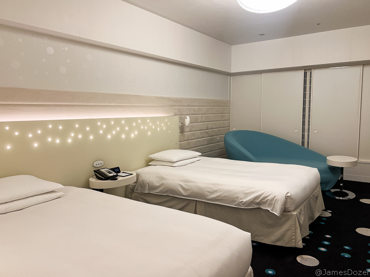 a room with two beds and a blue chair