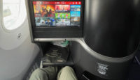a person's legs in a chair with a screen on the side of the seat