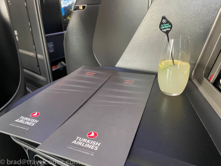 a glass of drink and a menu on a table