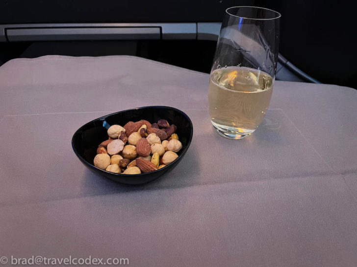 a bowl of nuts and a glass of wine