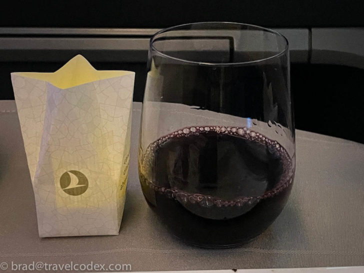 a glass of wine next to a bag of food