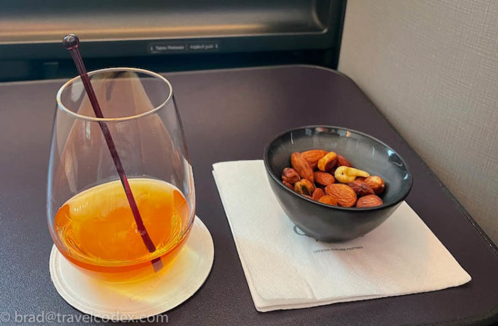 a bowl of nuts and a drink on a napkin