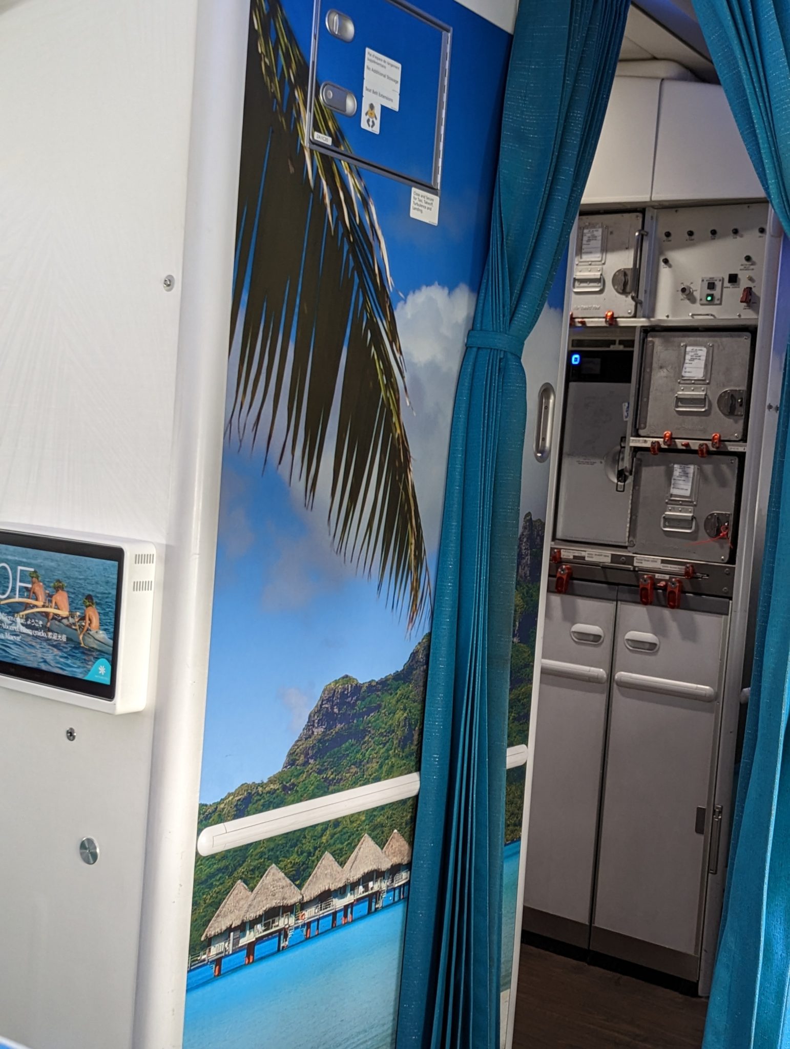 a room with a blue curtain and a wall with a picture of a beach and palm tree