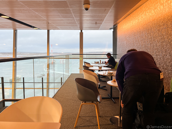 people sitting at tables in a room with a glass railing
