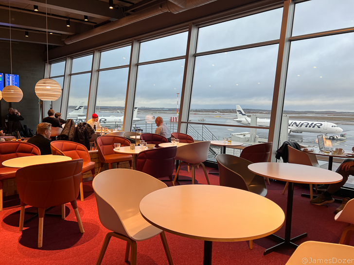 a group of people sitting at tables in a room with large windows