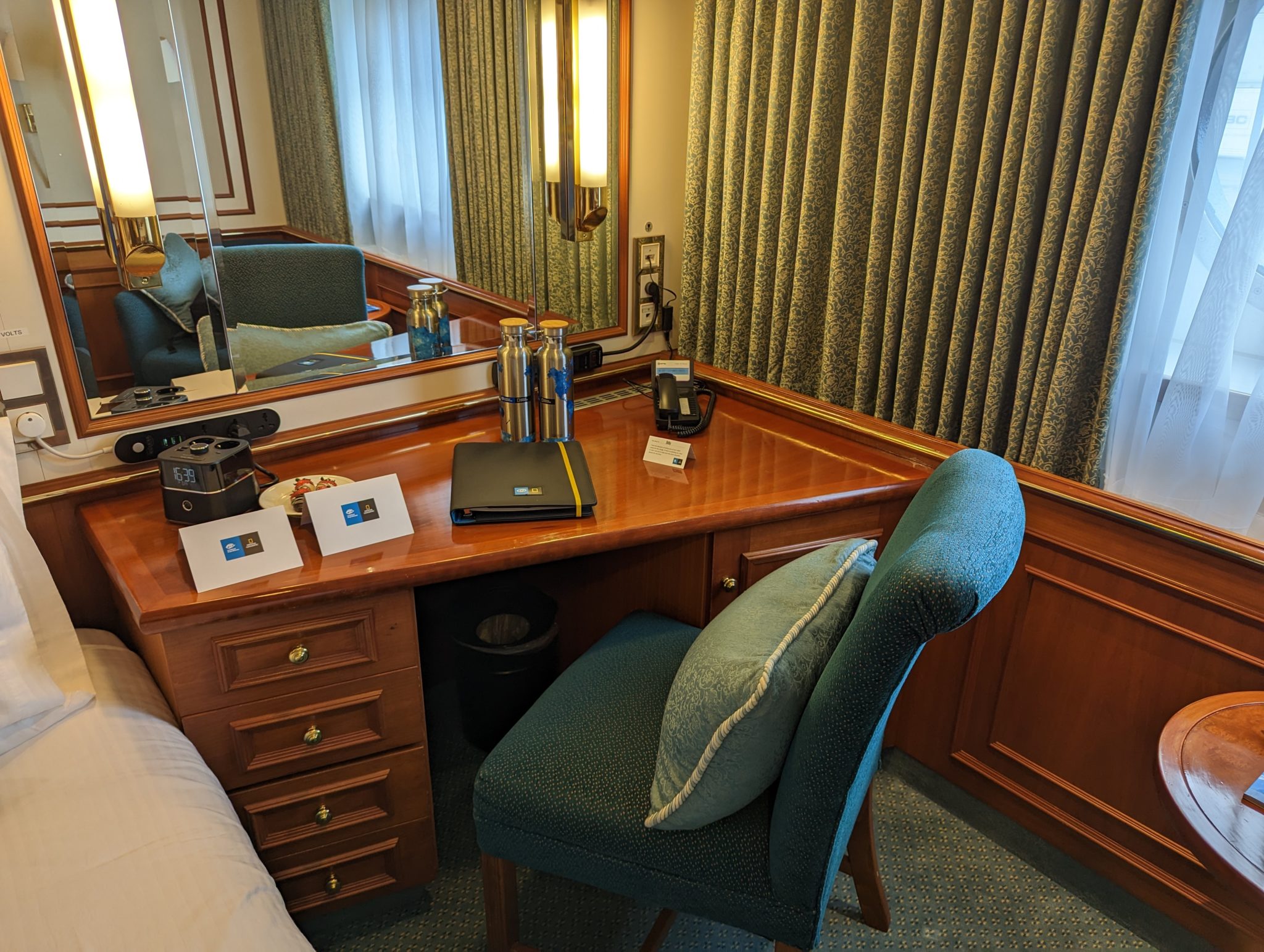 a desk with a chair and a mirror in a hotel room