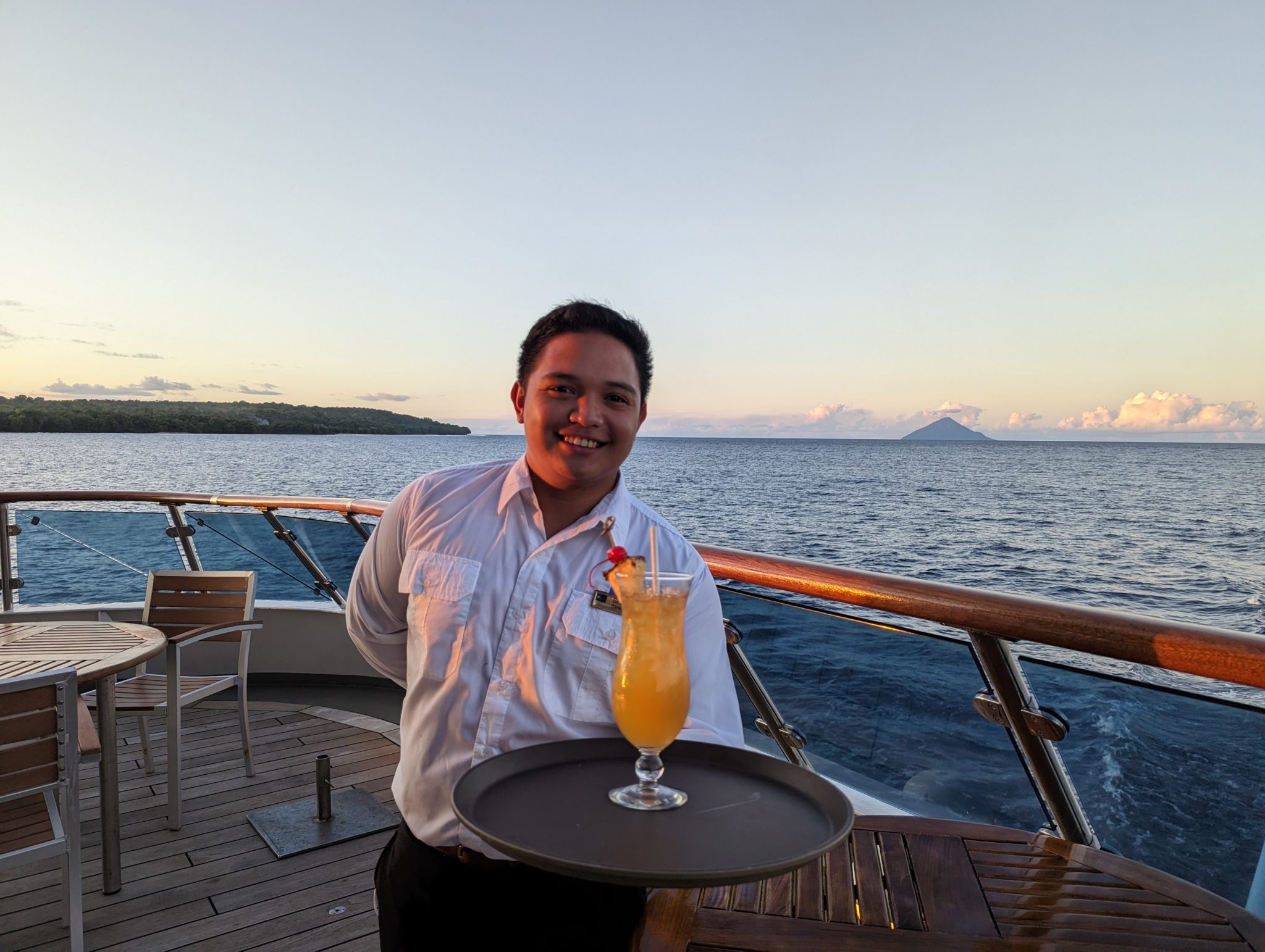 a man holding a tray with a drink on a boat
