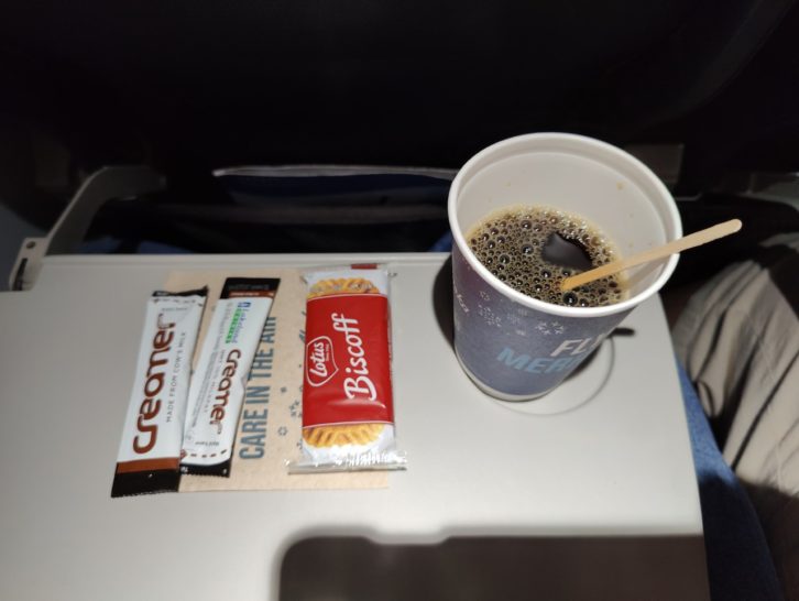 a cup of coffee and candy on a tray