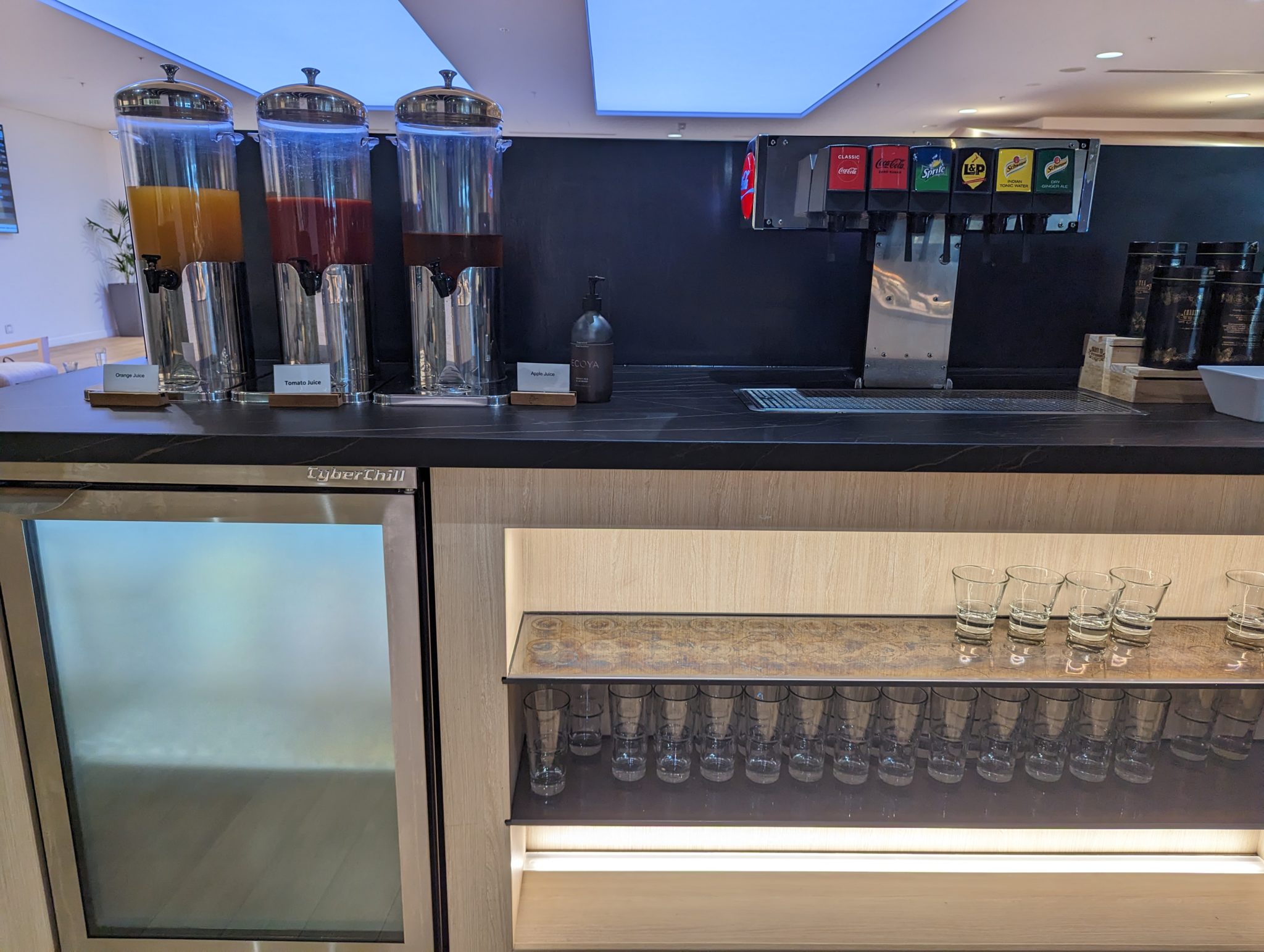 a counter with drinks dispensers and glasses