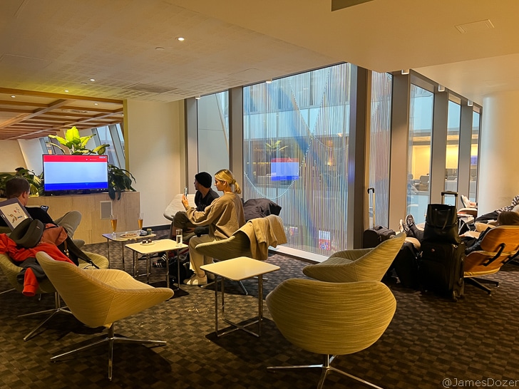 a group of people sitting in chairs in a room with large windows