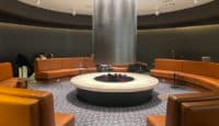 a room with a round fireplace and brown leather couches