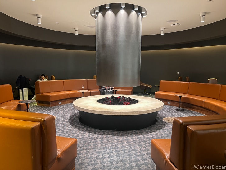 a room with a round fireplace and brown leather couches