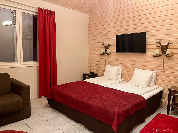 a bedroom with a red blanket and a tv on the wall