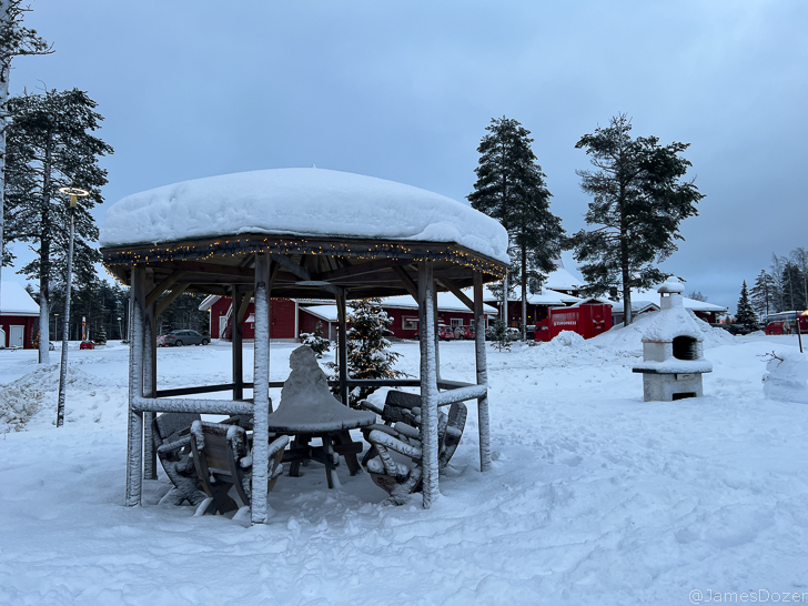 a snow covered gazebo with a table and chairs