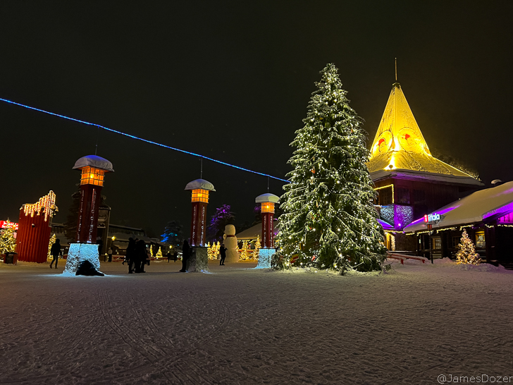 a building with lights and trees in the snow