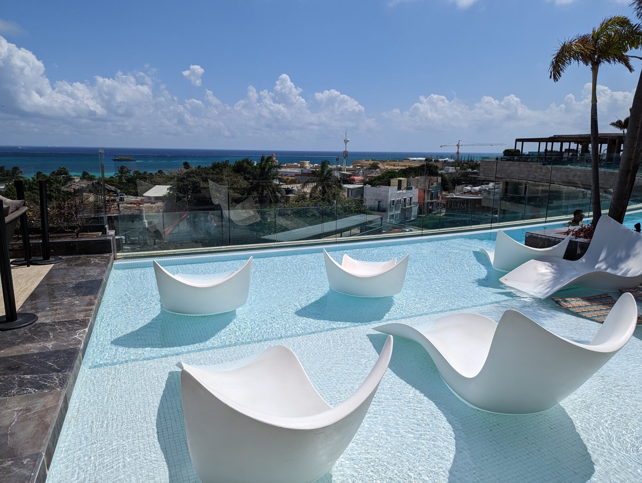 a pool with chairs and a view of the ocean