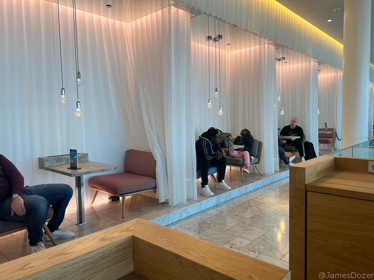 a group of people sitting in a room with white curtains