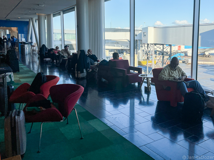 people sitting in a room with red chairs and a large window