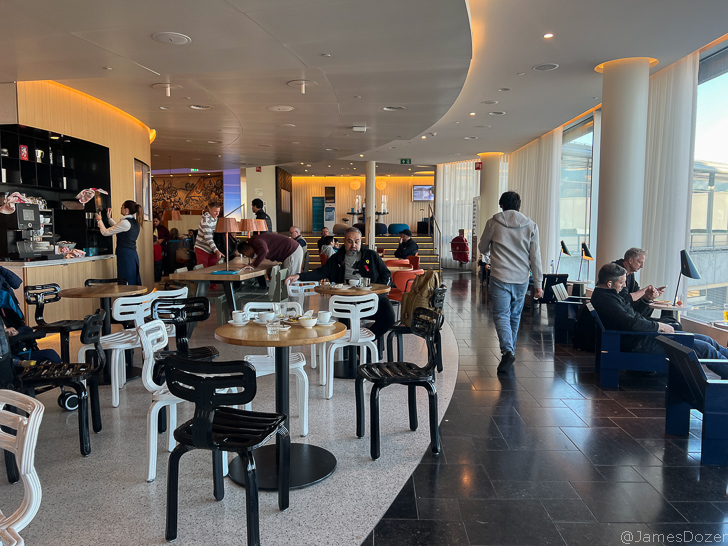 a group of people sitting at tables in a room with a large window
