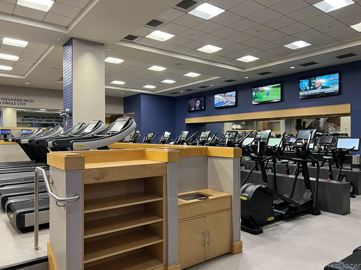 a room with treadmills and a row of screens