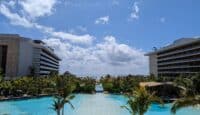 a pool with palm trees and buildings in the background