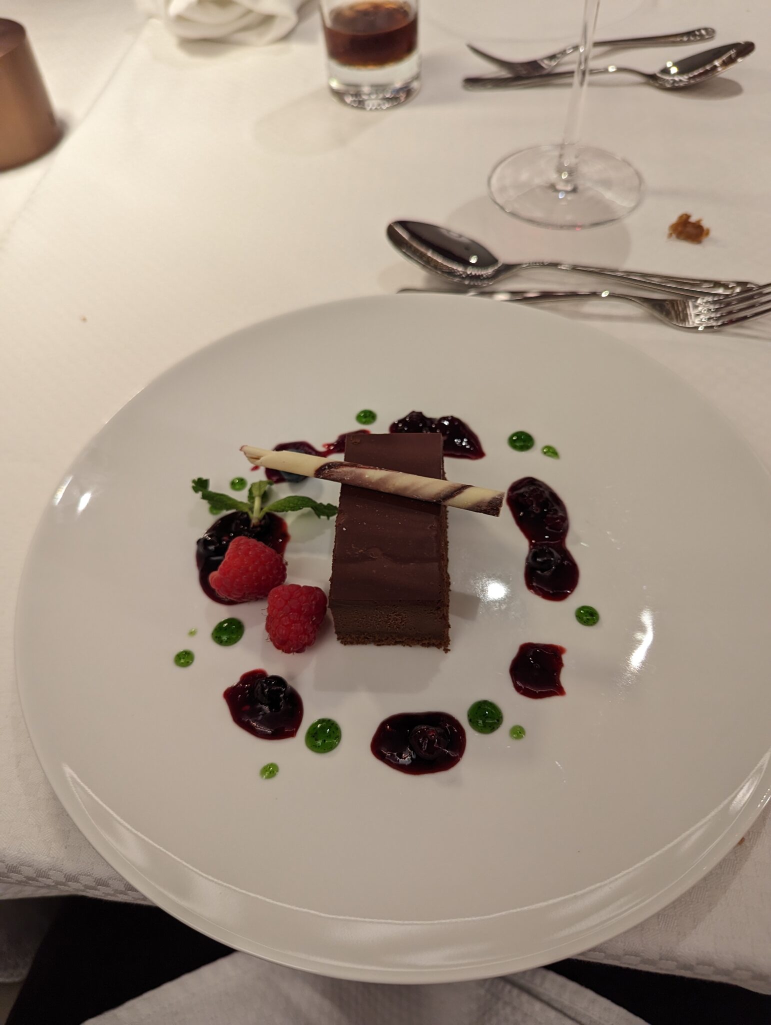 a plate of dessert with berries and a glass of wine