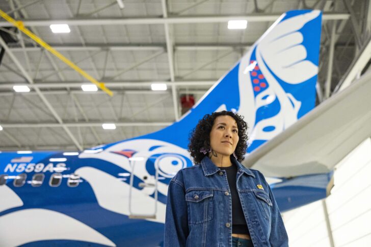 a woman standing in front of a blue and white airplane