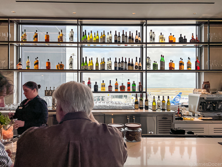 a group of people sitting at a bar with bottles of alcohol