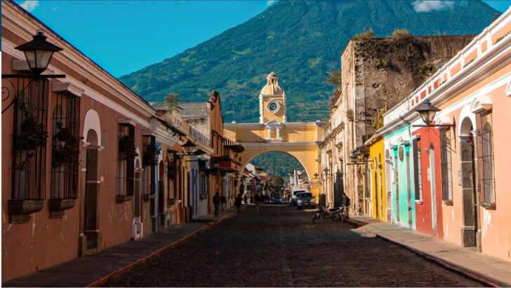 a street with a clock tower and a mountain in the background