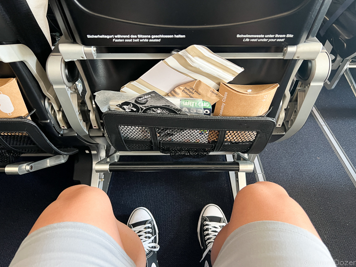 a person's legs and a basket of food in a seat