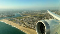an airplane wing and engine above a beach