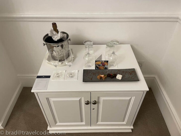 a white cabinet with a silver bucket and glasses on it