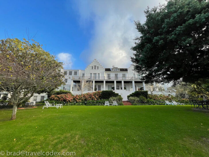 a large white house with lawn and trees