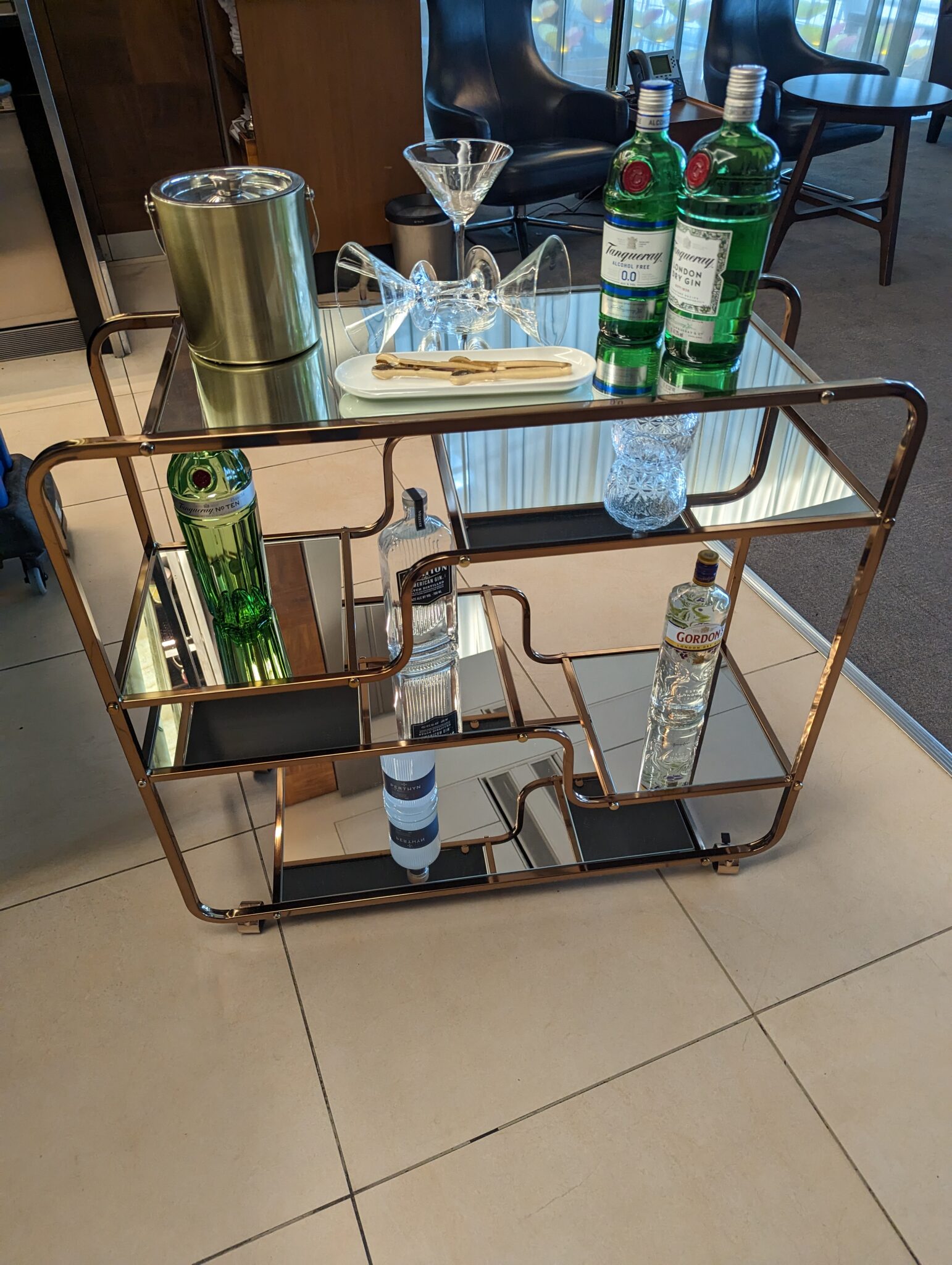 a bar cart with bottles and glasses on it