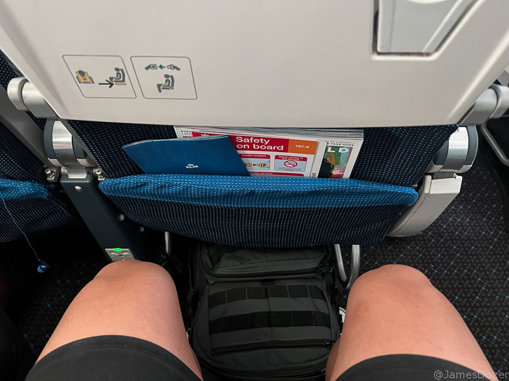 a person's legs in a seat with a bag in the back